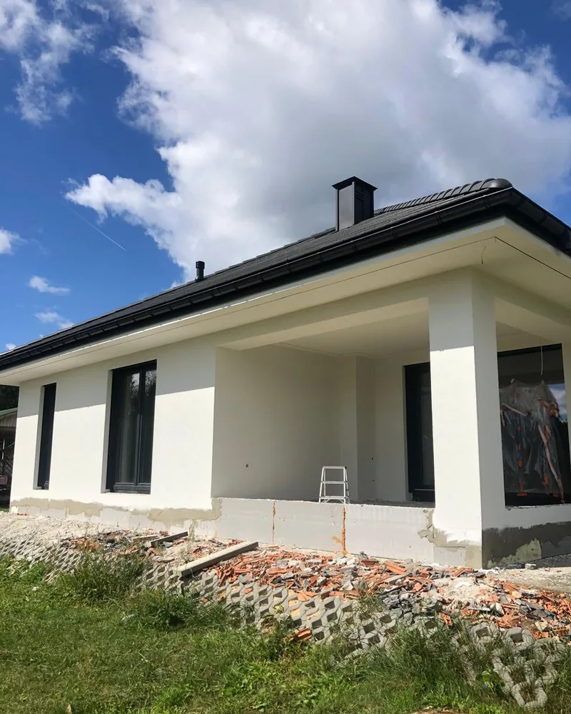 Dom showroomowy w Korzonku, wrzesien 2026 - elewacja w bialym tynku, cokol jeszcze surowy