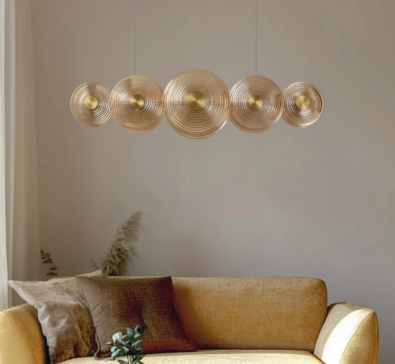 Lampa wisząca Nazar z pięciu bursztynowych szklanych dysków nad musztardową sofą w salonie — Azzardo