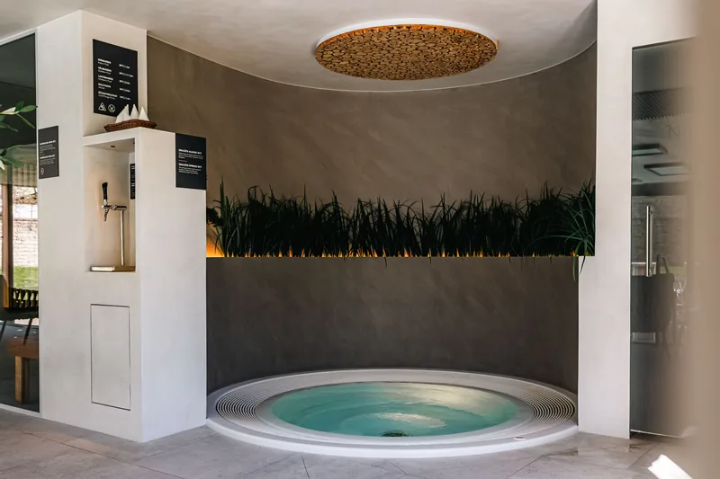 Wanna jacuzzi we wnęce z zaokrągloną ścianą pokrytą ciemnym mikrocementem Basebeton - strefa SPA — Basebeton