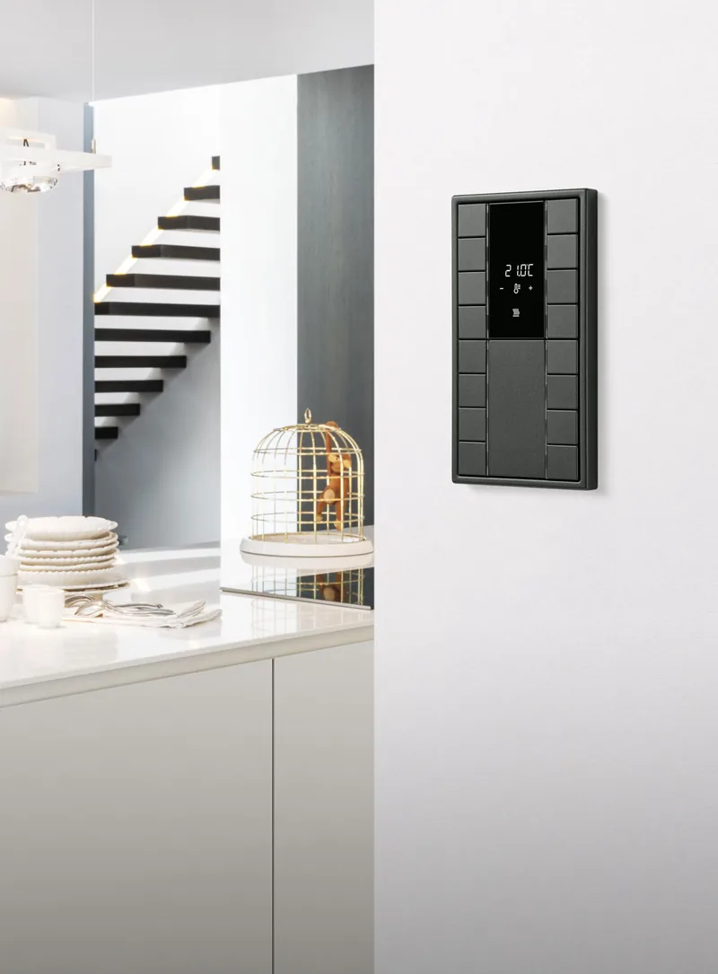 Czarny panel JUNG KNX w białej kuchni ze schodami w tle — JUNG