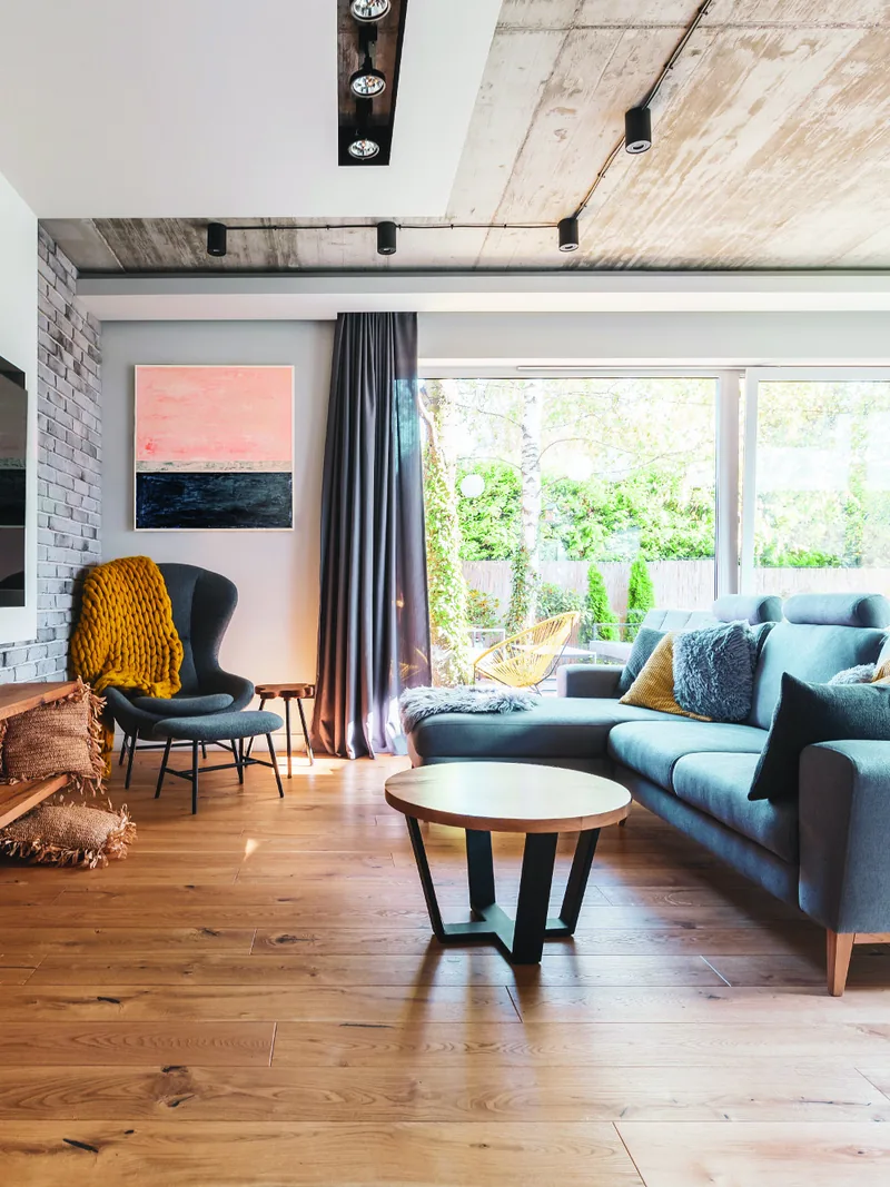 Salon z betonowym sufitem, granatową sofą i żółtym kocem, szeroka deska dębowa — Holz Floors