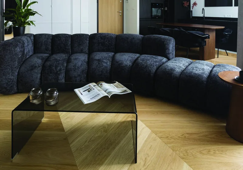 Salon z ciemną modułową sofą i szklanym stolikiem, dębowa jodełka francuska — Holz Floors
