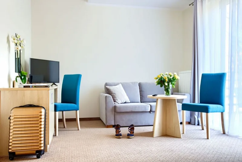 Pokój hotelowy z jasną wykładziną i niebieskimi krzesłami — Ampel