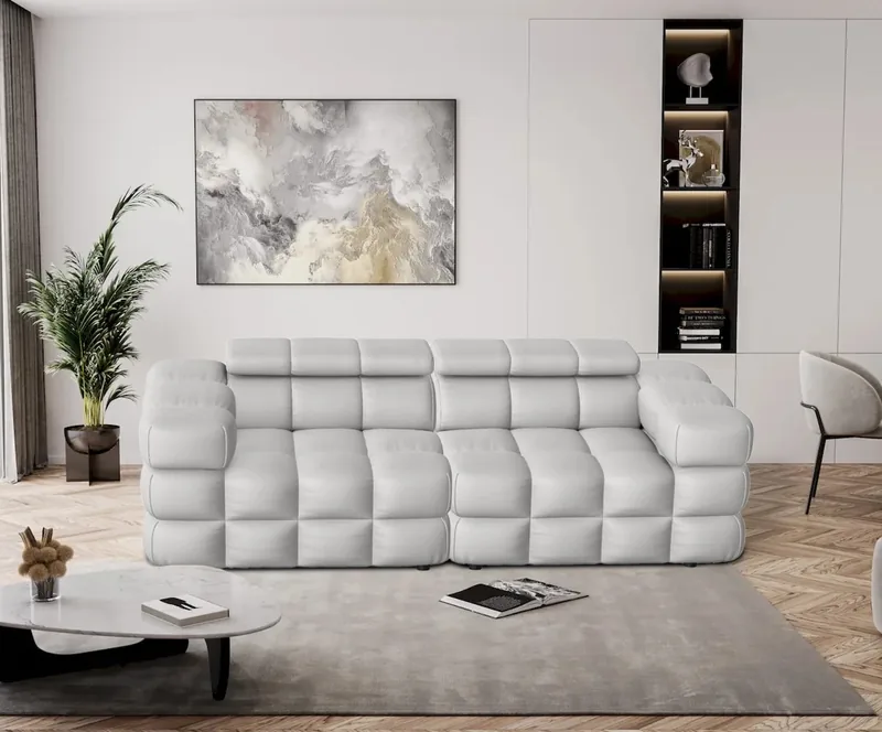 Biala sofa z pikowanym siedziskiem i regulowanymi zaglowkami, wnekowy regal i obraz nad sofa. Wizualizacja 3D.