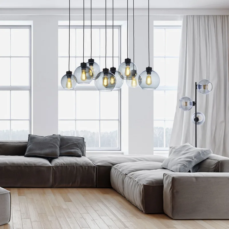 Szklane kule CUBUS w oknie salonu nad szara sofa