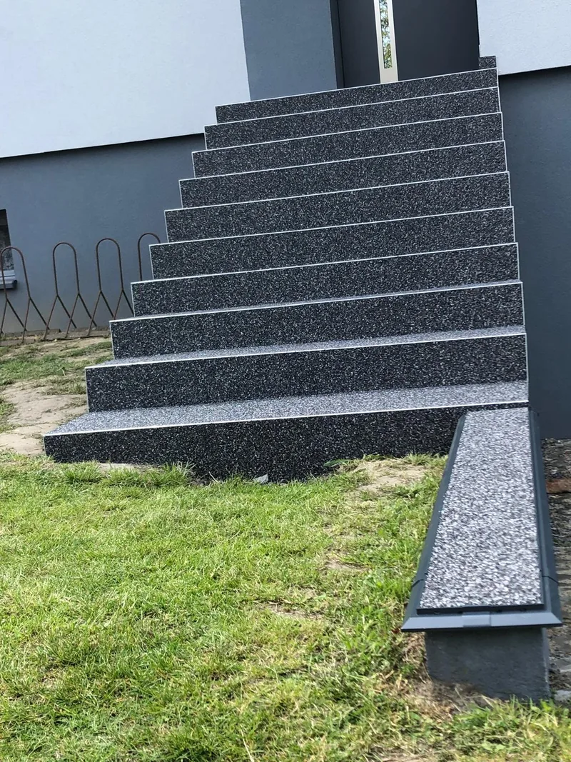 Schody przy elewacji — ciemny kamienny dywan — realizacja LuxBud Design, Częstochowa